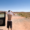 Travel photograph of a man changing his shirt in the middle of nowhere