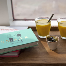 A photo of two juices with straws, mixed olives and books