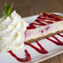 Close-up of a strawberry cheesecake with whipped cream