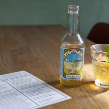Table with a menu, a bottle of ginger ale and a glass