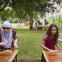 Moslima met zonnebril en dochter die aan het sjoelen zijn in Moerwijk, Den Haag
